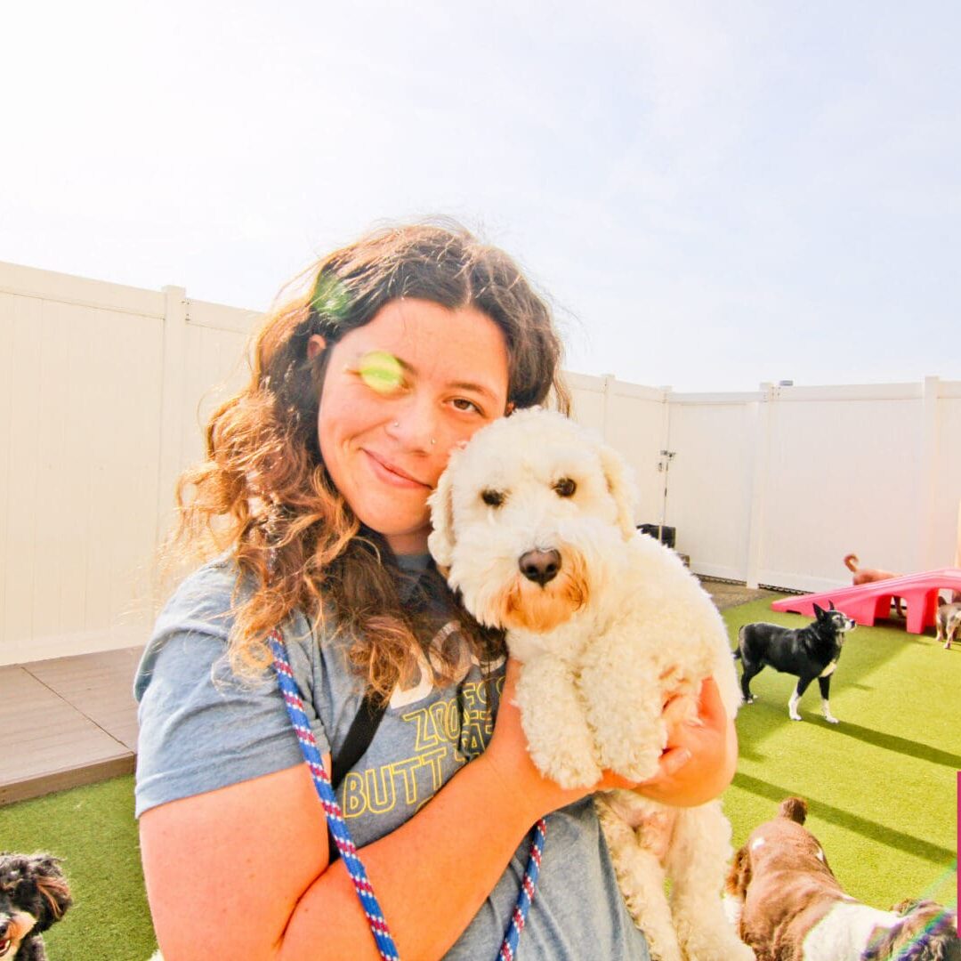 Smiling woman holding fluffy dog outdoors.