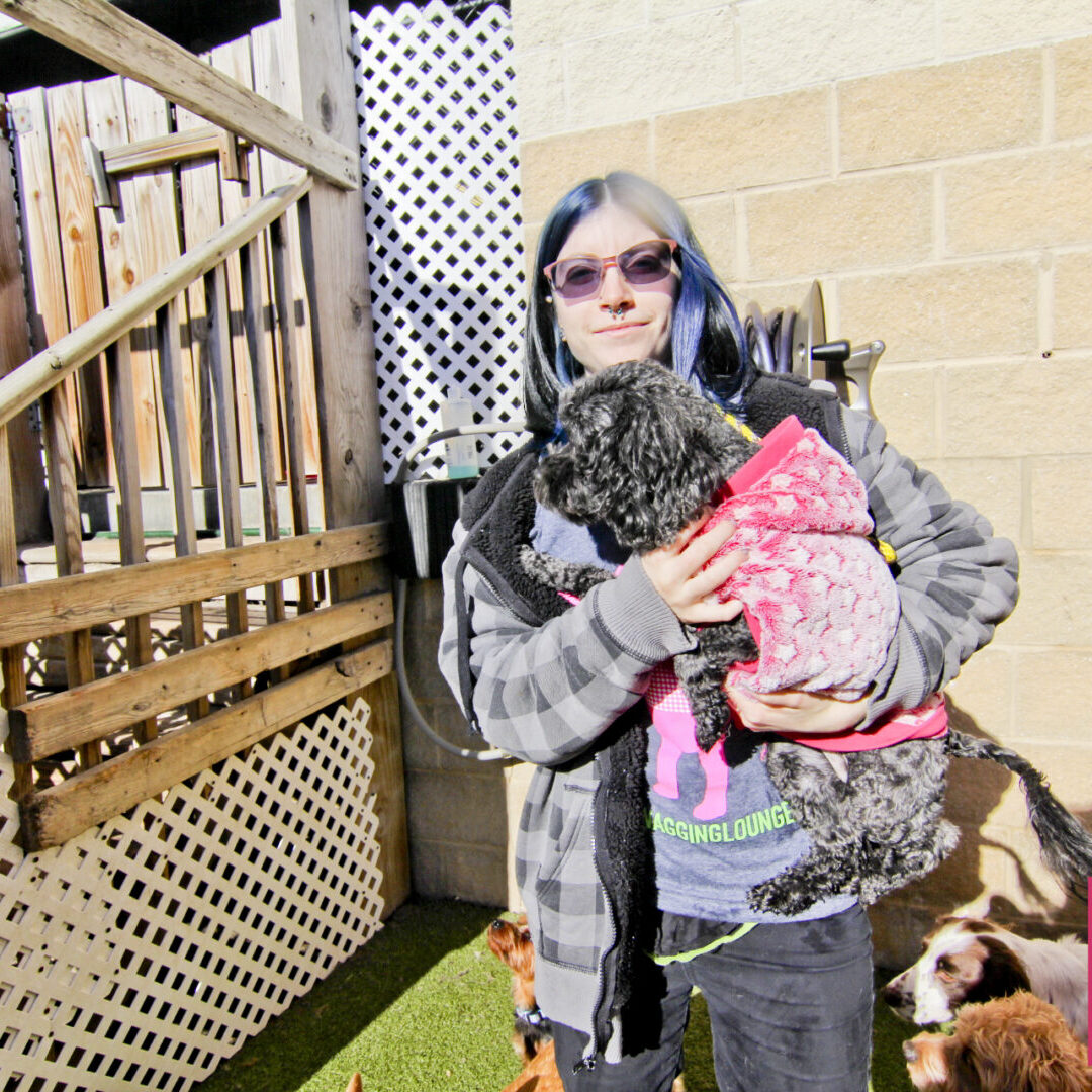 A woman holding her dog in front of stairs.